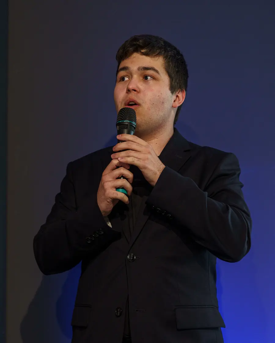 Dominik speaking on stage with a microphone